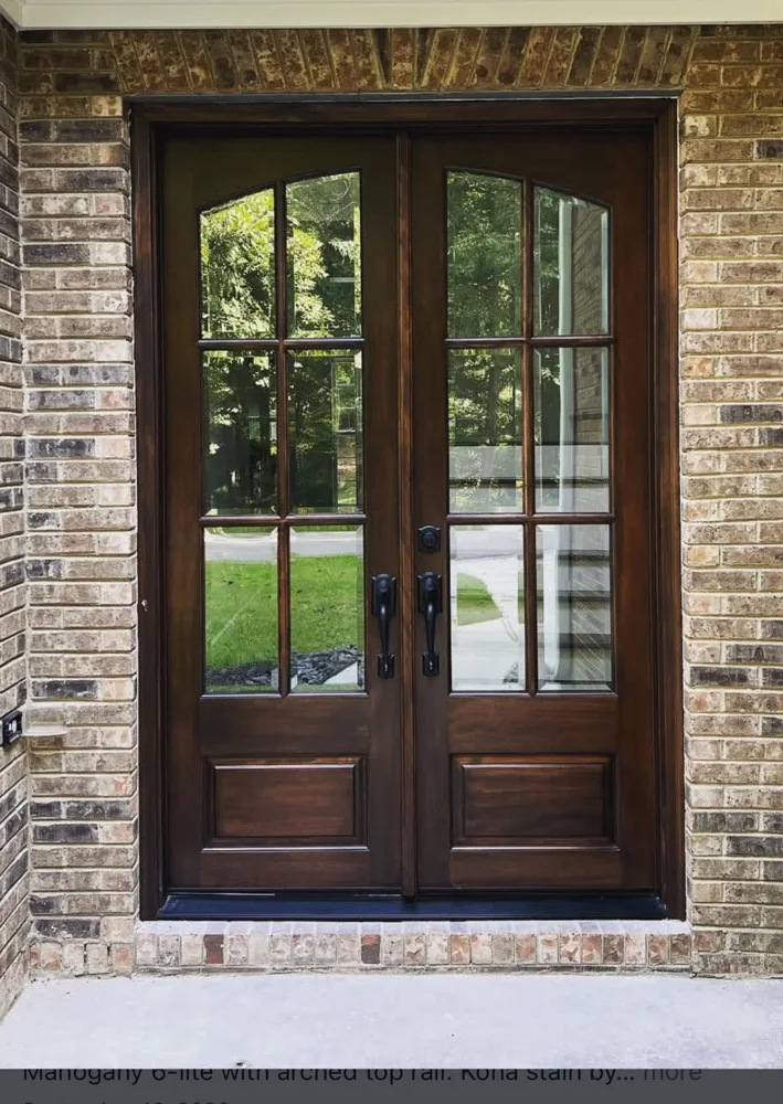 Wood double entry doors beneath an arched top rail