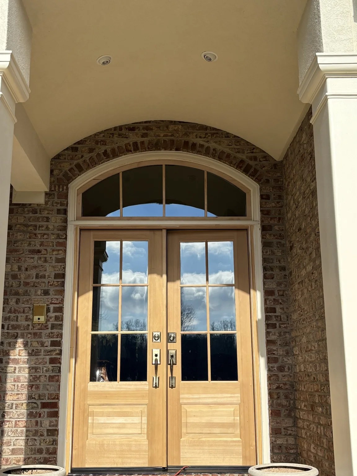 Natural wood double entry doors with an arched transom