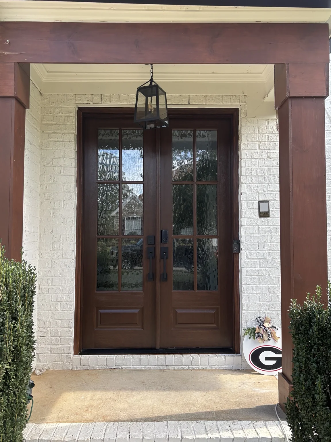 Dark wood double entry doors set in white brick