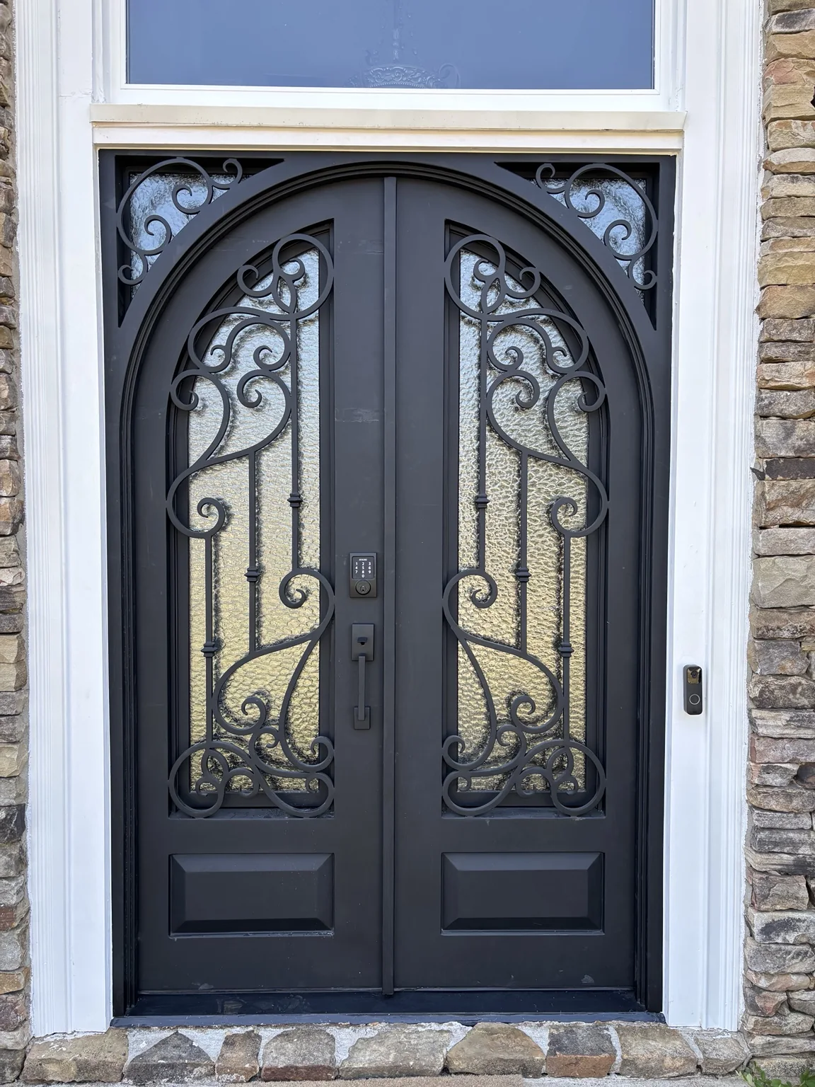 Black double entry doors with decorative ironwork and textured glass