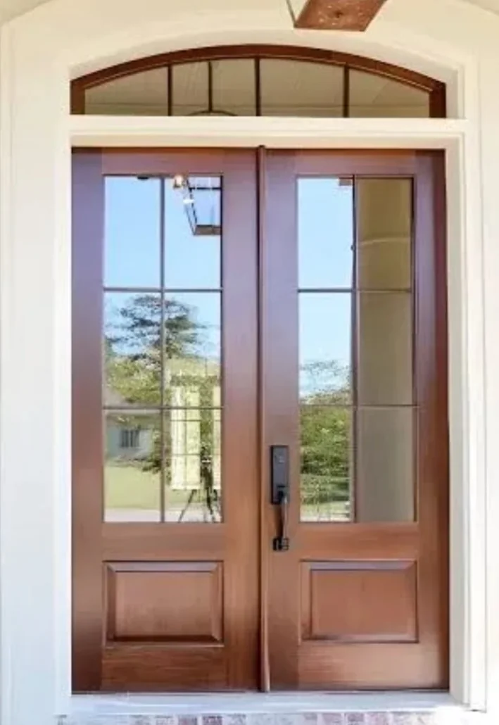 Wood double entry doors with glass panes and an arched transom