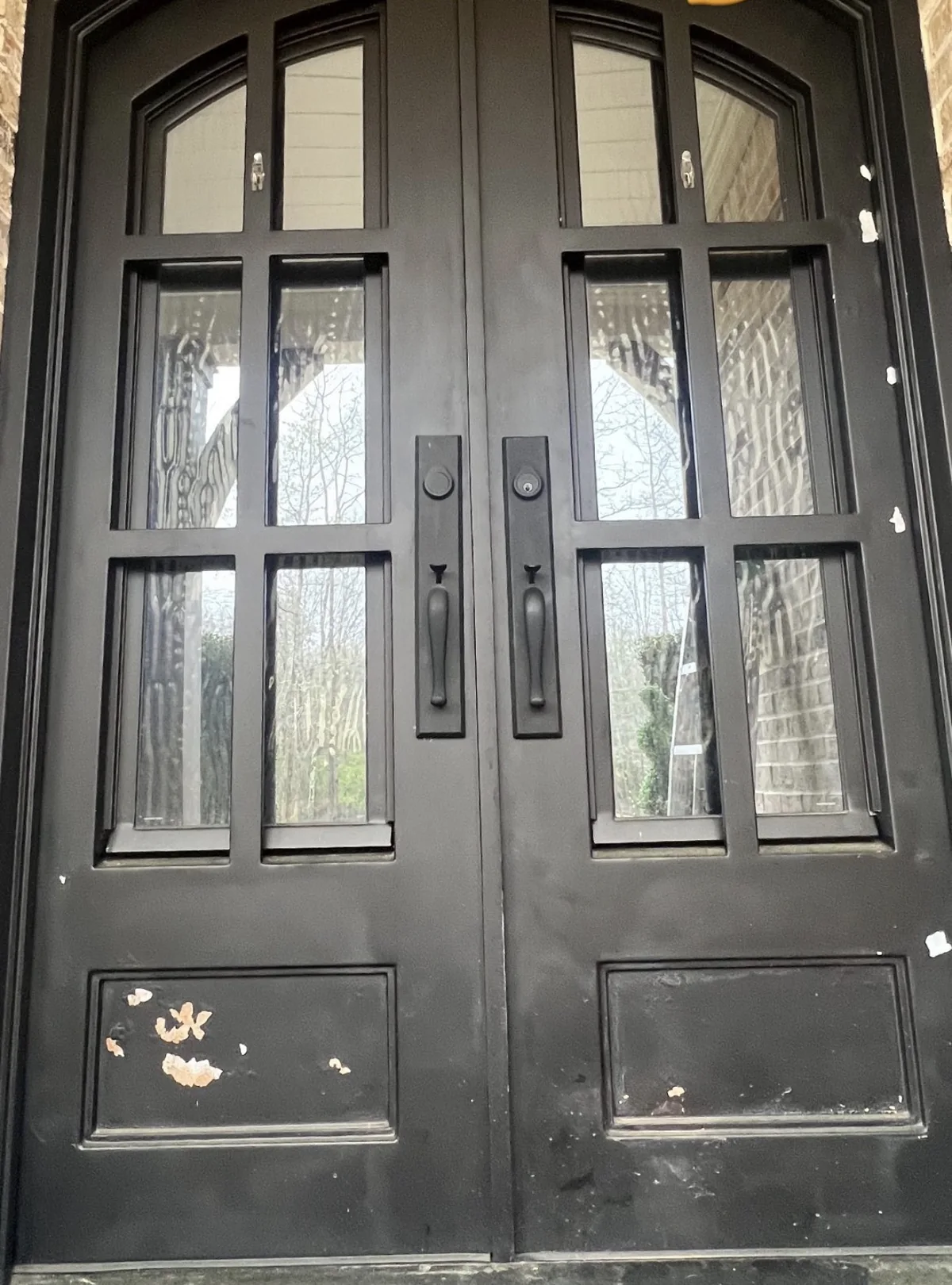 Black double entry doors before refinishing with visible wear and chipped finish